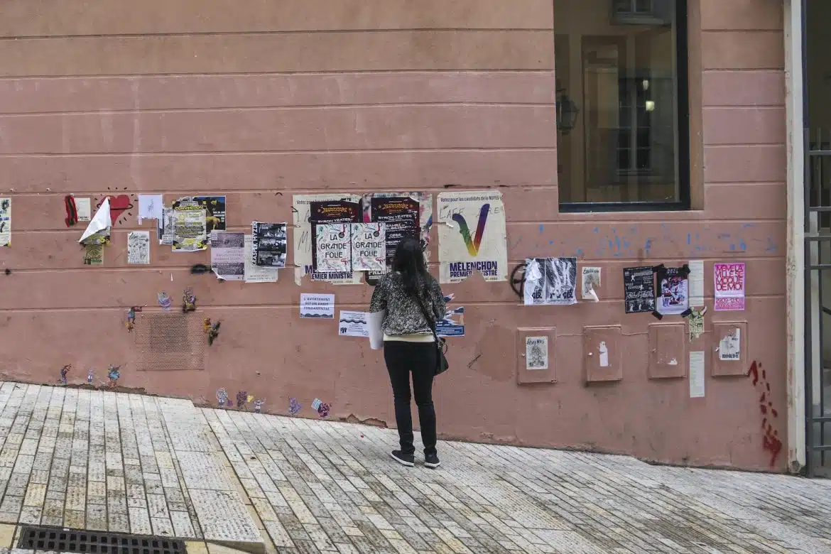 a person standing in front of a wall with posters on it